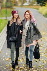 Two girls talking to each other and laughing, autumn clothing