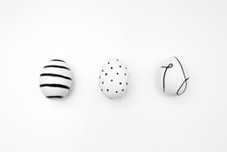 Easter eggs with a minimalistic black pattern. Ornament of stripes, lines and dots. Chicken eggs with a pattern on a white background. Festive card for the holiday Happy Easter