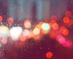 Image of raindrops on window at night in the city