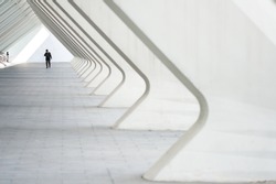People in the architectural perspective. The sloping lines of the architecture. The man in the suit comes in a bright corridor in a modern building