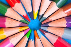Wooden color pencils lie on a circle. The tips of the pencils look in the center of the circle. The concept of creativity