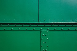 The green background. Painted metal surface. The metal surface is sealed with rivets. Metal painted green.