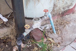A water meter is installed on the side of the house.