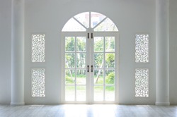 The light shines on the white door. When look outside, there is a green tree. Look so refresh.