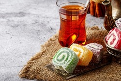 Traditional Turkish delight with Turkish tea on gray background. Ramadan Kareem celebration concept. Fragrant Turkish tea and Turkish sweets in national dishes.