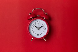 red alarm clock on red background. close up shot. top view.