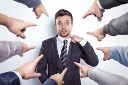 Many fingers pointing at a businessman
