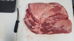 Beef shoulder clod next to a 6 inch butcher's knife