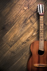 Classical six-string guitar on a wooden surface; Dark photo, rustic (Vertical position)