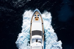 View from above, stunning aerial view of a luxury yacht cruising on a blue water creating a wake. Costa Smeralda, Sardinia, Italy.