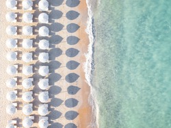 Aerial view of amazing beach with white umbrellas and turquoise sea at sunset. Mediterranean sea, Sardinia, Italy.