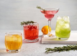 Four colorful summer cocktails in glasses on  white table. Assortment of fresh  summer drinks. Pink and red sangria cocktails, orange punch cocktail, margarita cocktail, tropical mule.