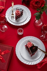 Valentines day dinner with table place setting with red gift, red roses,  with chocolate cake. View from above.Valentines day dinner concept
