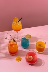 Colorful tropical cocktails. Refreshing colorful summer drinks on pink background with shadow palm leaf. Bar drinks menu.