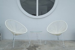 
Two wicker chairs with congret wall as backdrop