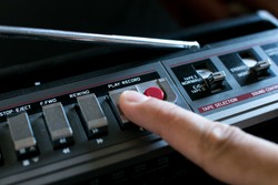 Finger pressing the Play button on an old stereo 80's