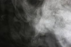 steam in a beam of light from a boiling kettle on a dark background
