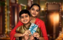 Indian Brother give gift to sister on Raksha Bandhan on dark background