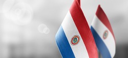 Small national flags of the Paraguay on a light blurry background
