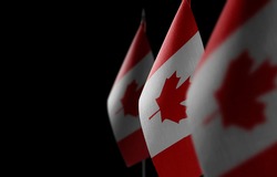 Small national flags of the Canada on a black background