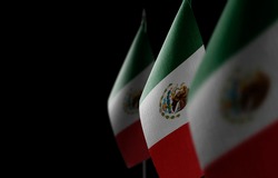 Small national flags of the Mexico on a black background