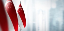 Small flags of Singapore on a blurry background of the city