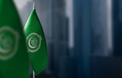 Small flags of Arab League on a blurry background of the city