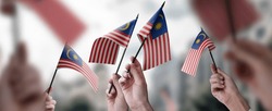 A group of people holding small flags of the Malaysia in their hands.