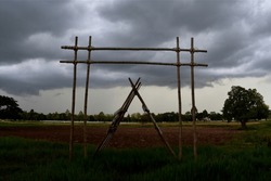 bamboo entrance gate structure into an agricultural field under grey rainstorm cloud background