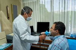 Mature man performing pulmonary function test and spirometry at doctor office
