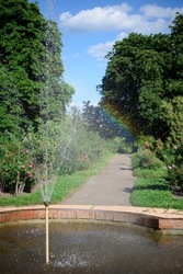 Fountain in the park. Rainbow from the sun and water drops. 