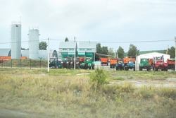 Many tractors in agricultural enterprise, motor transport depot, on cloudy day in country