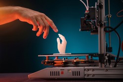 3D printing in progress. 3d printer printed a hand. A man touches the product printed on a 3d printer. God's touch, biblical motives. High quality photo