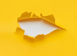 Big torn hole in yellow paper with a white background. Concept for placing text or other elements, copy space, mockup.