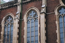 Three old pointed gothic windows with stained glass on facade of the building. Baroque and Gothic architecture. Church of St. Olga and Elizabeth. Lviv, Ukraine.