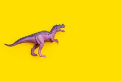 Plastic dinosaur toy on yellow background. Top view