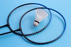 Shuttlecock and badminton rackets on blue background.
