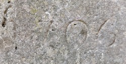 The year 1706 carved into stone and partly effaced – a detail of an inscription produced that year. Covered with lichen