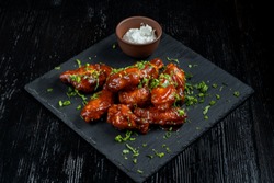 Chicken Wings with tomato barbecue sauce. In a small bowl of horseradish. Diagonal view.
