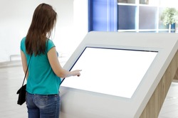 Woman is using a blank touch screen of interactive information stand in the supermarket.