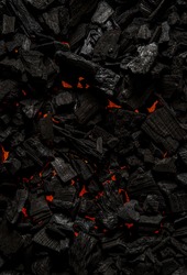 Black charcoal with red streaks of heat. Black textured background.