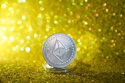 The reverse side of the silver ether. Cryptocurrency ether is the coin of the future. Silver ether. Golden shiny background. High quality photo