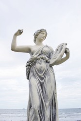 Statue woman with lyre. Sculpture sea and sky background.
