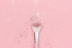 Makeup brush and shiny sparkles on pastel pink background. Festive magic makeup concept. Template for design, Top view Flat Lay Copy space.