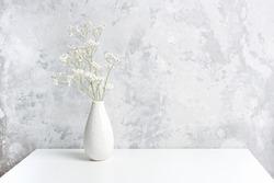 Bouquet of white small delicate flowers gypsophila in vase on table agains gray stone wall. Copy space Minimal style. Template for postcard, text, design Concept Women's day, Mothers Day.