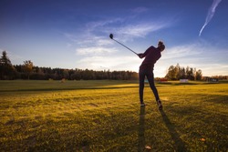 Playing golf in autumn evening during golden hour in Lithuania