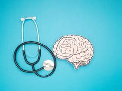 A stethoscope and brain shape made from paper over a blue background. Awareness of Alzheimer's, Parkinson's disease, dementia, stroke, seizure, or mental health. Neurology and Psychology care