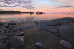 Beautiful pink sunset on Lake Ladoga in Karelia, Russia in the Ladoga Skerries national park in summer. Natural landscape with water rocks, stone islands and forest near shore