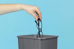 throw glasses in trash bin, glasses in hand in front of trash can, vision treatment concept