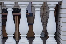 part of the terrace from a row of white concrete columns on a gray brick wall on the street